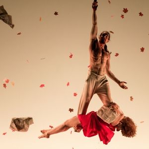 Fotografía de dos actores flotando sobre un escenario en un fondo beige con hojas rojas de arce
