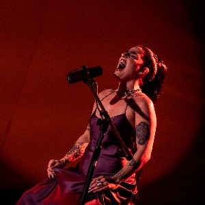 Una mujer canta sobre un fondo rojo intenso